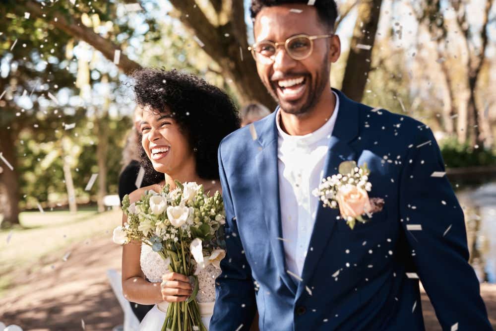 Wedding day couple smiling with confetti. 