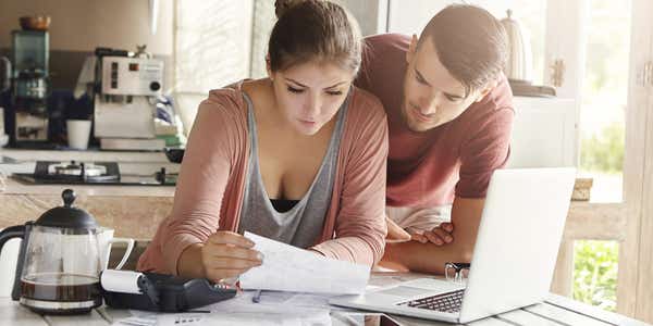 Young caucasian couple calculating domestic finances to pay off debt.