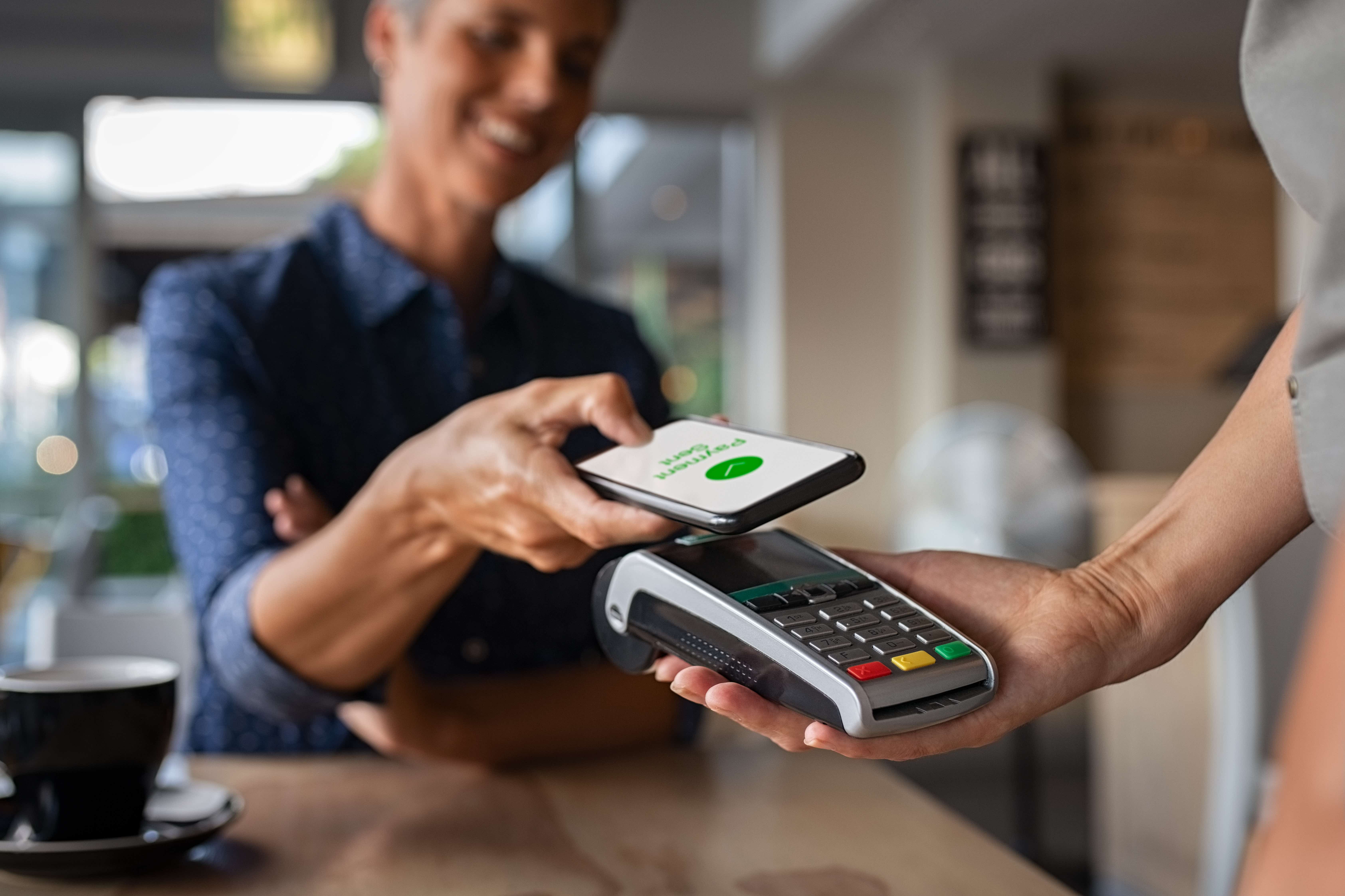 Woman paying with her phone in a shop using a contactless payment terminal