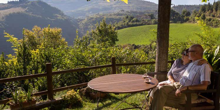 Older couple, sitting at patio table outside looking at the hillside view