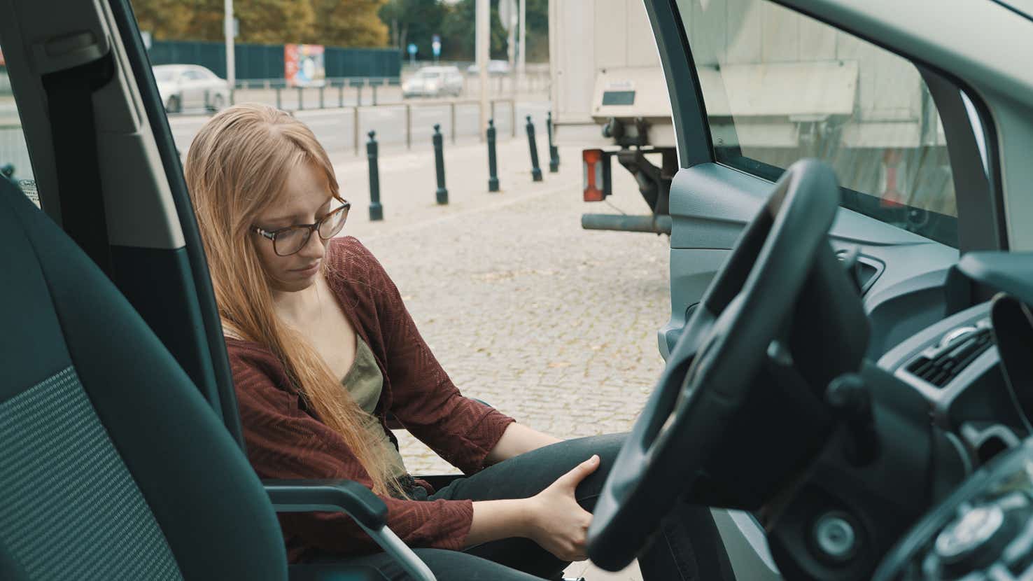 A wheelchair user getting into the driving seat of a car