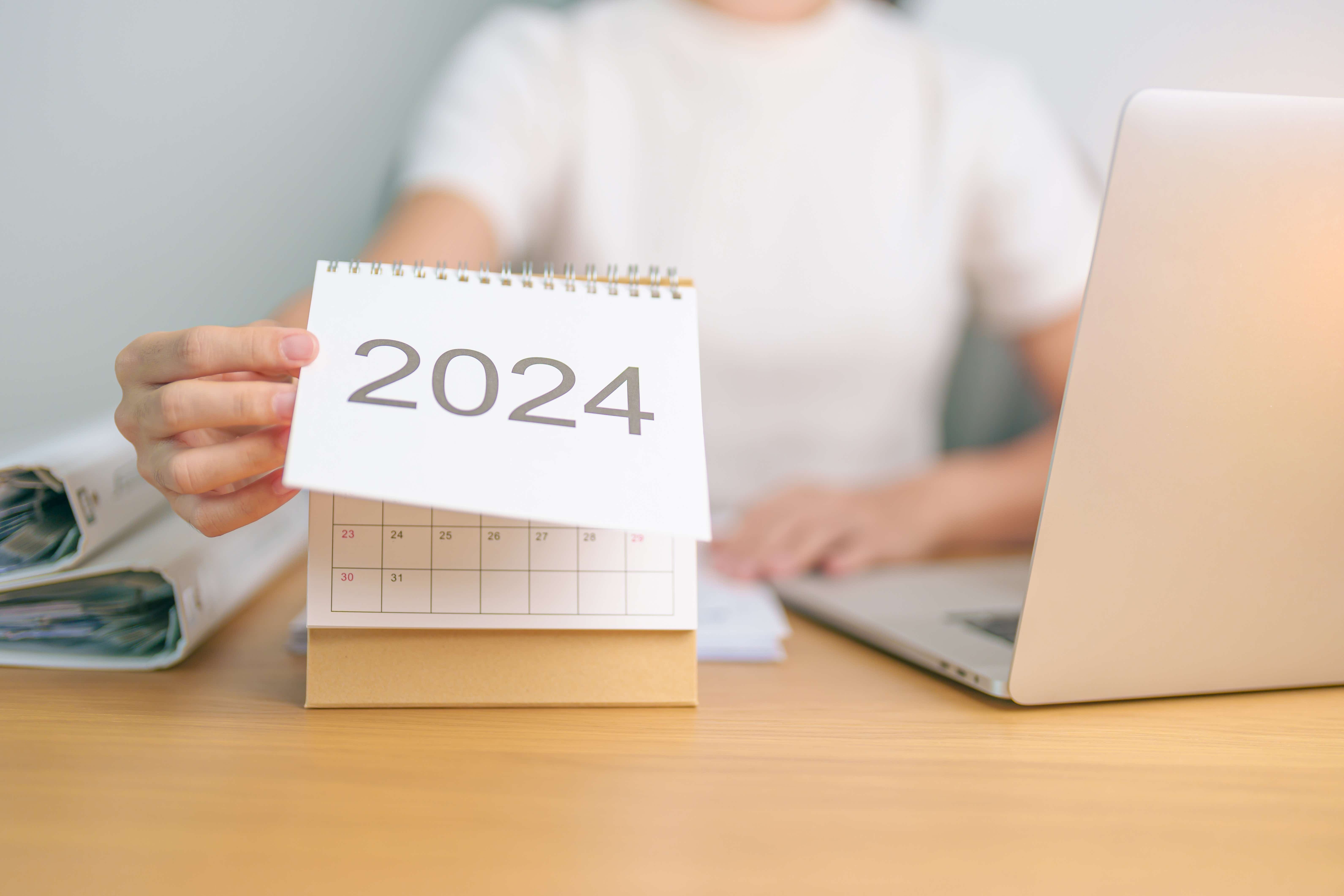 2024 year calendar on table with business woman using laptop computer. 