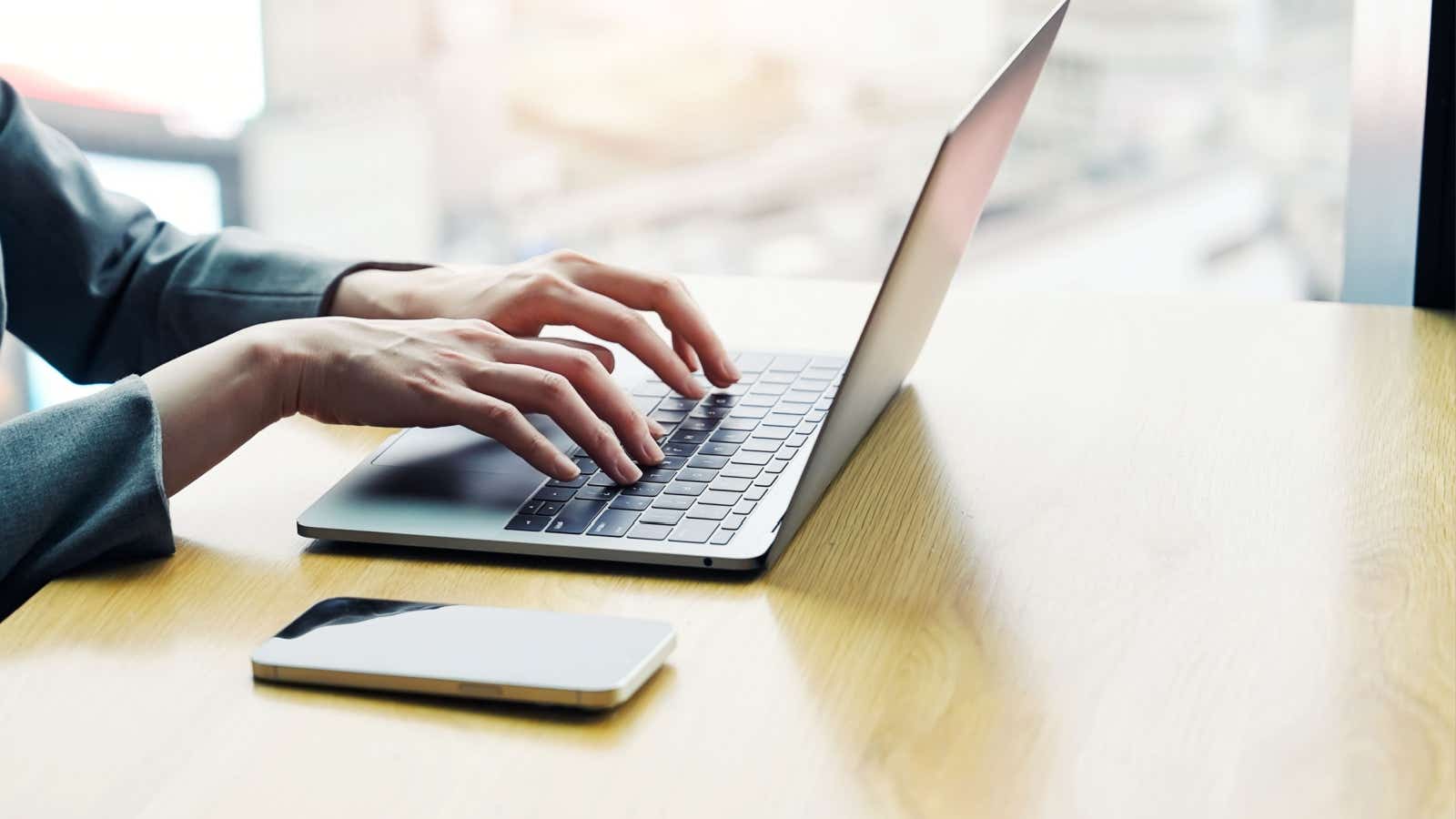 Hands typing on a laptop keyboard