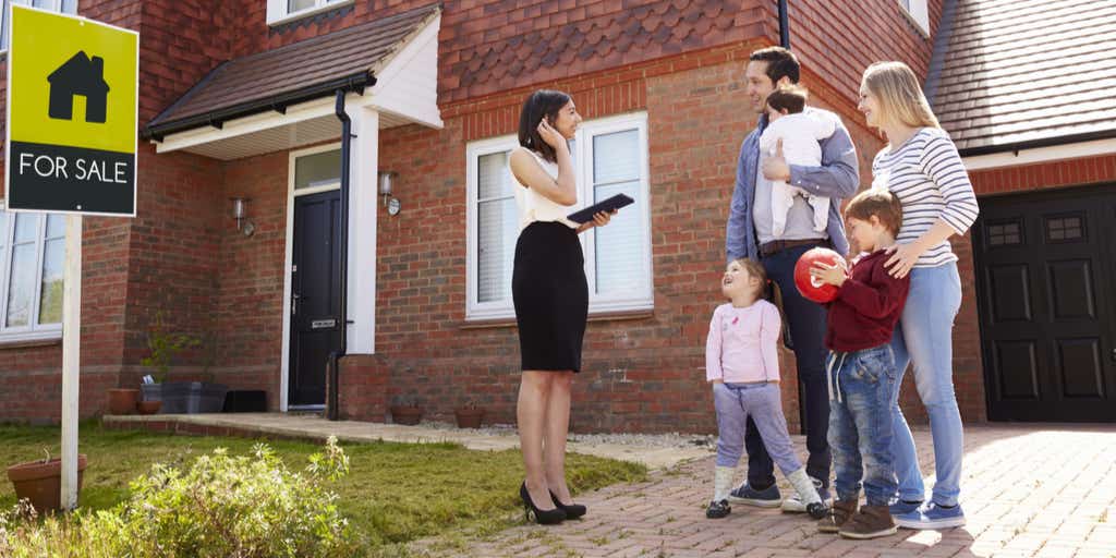 Estate agent outside house for sale speaking to family