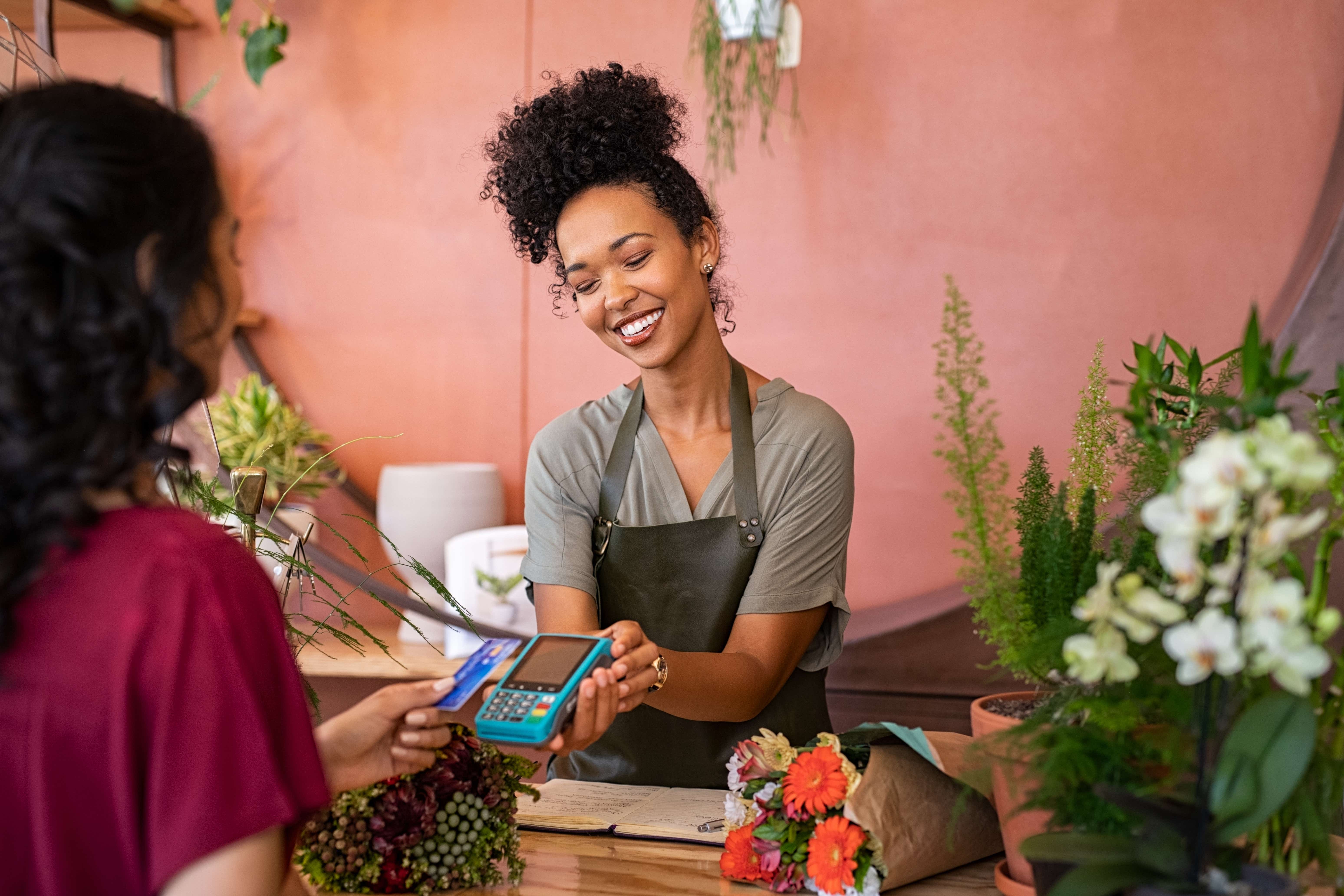 A young woman takes a card payment in her florist 