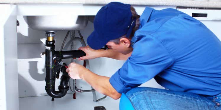 Plumber fixing some pipes under a sink.