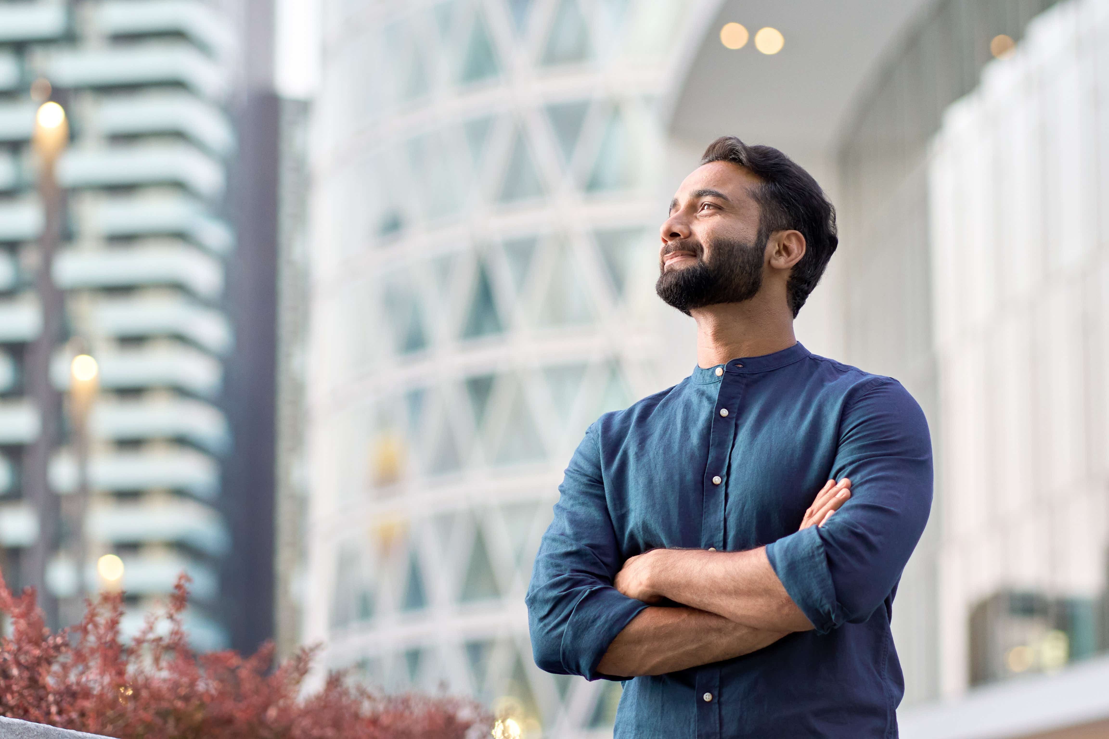 An Asian businessman smiles as he looks up in the city.