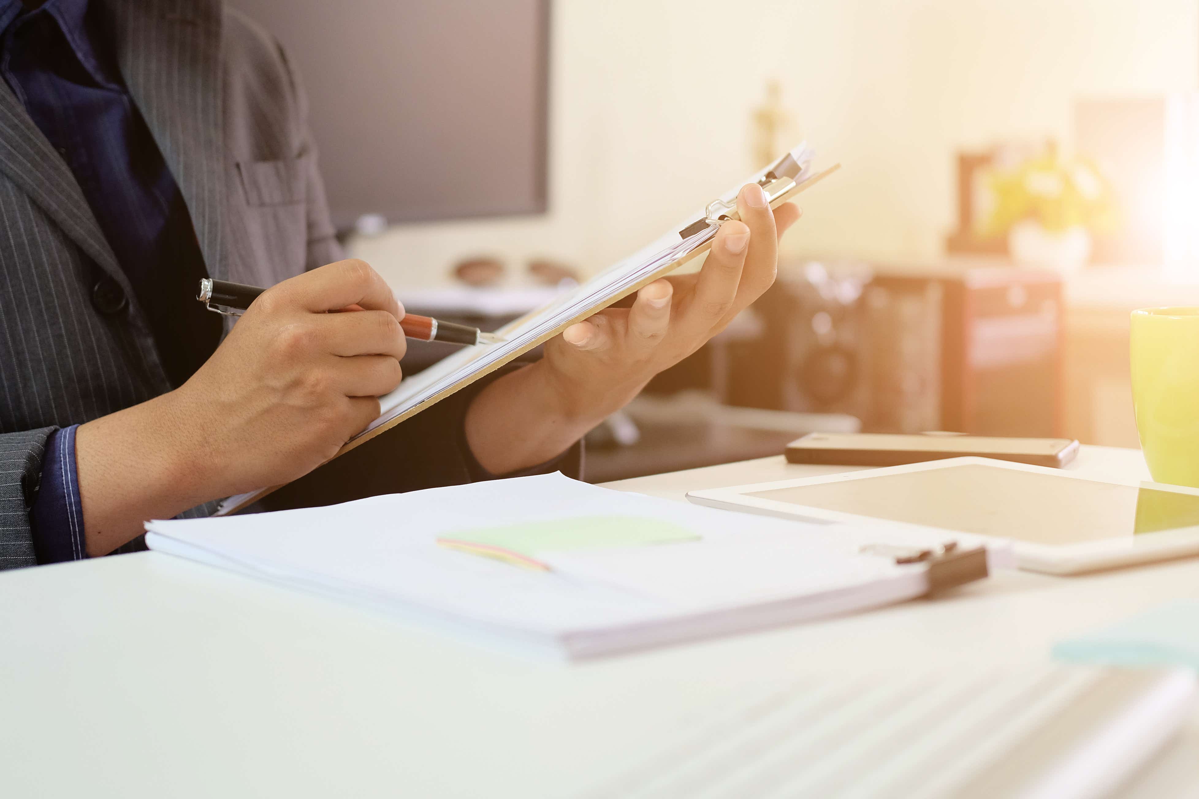 A hand holds a pen while going through a checklist