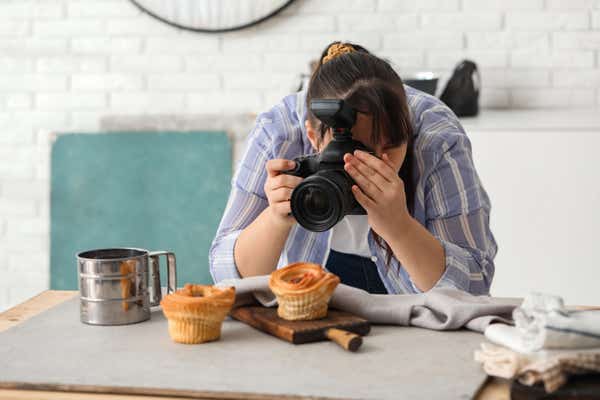 Woman using a digital camera to take photos of cakes.