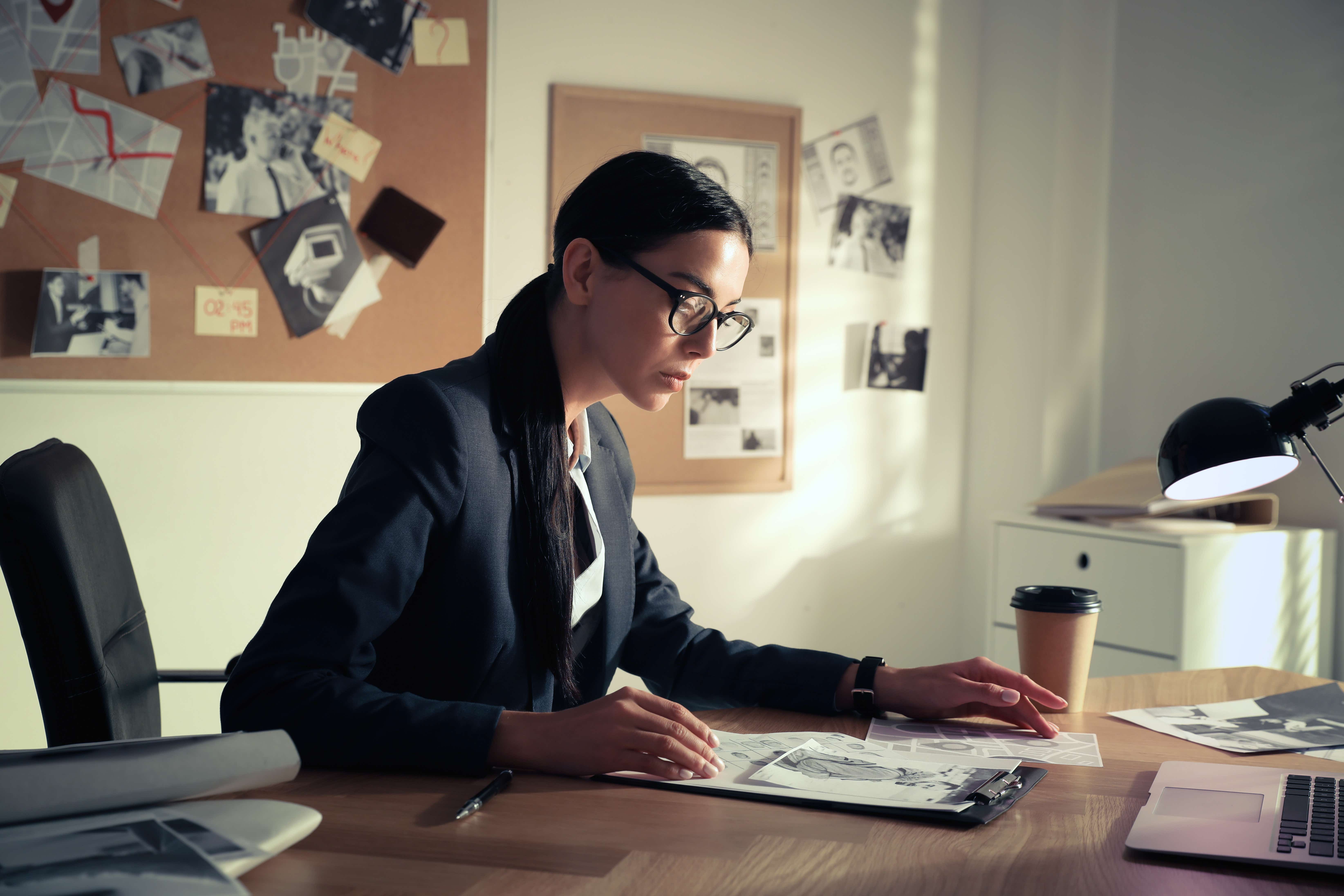 A woman in glasses at a desk in an office investigating