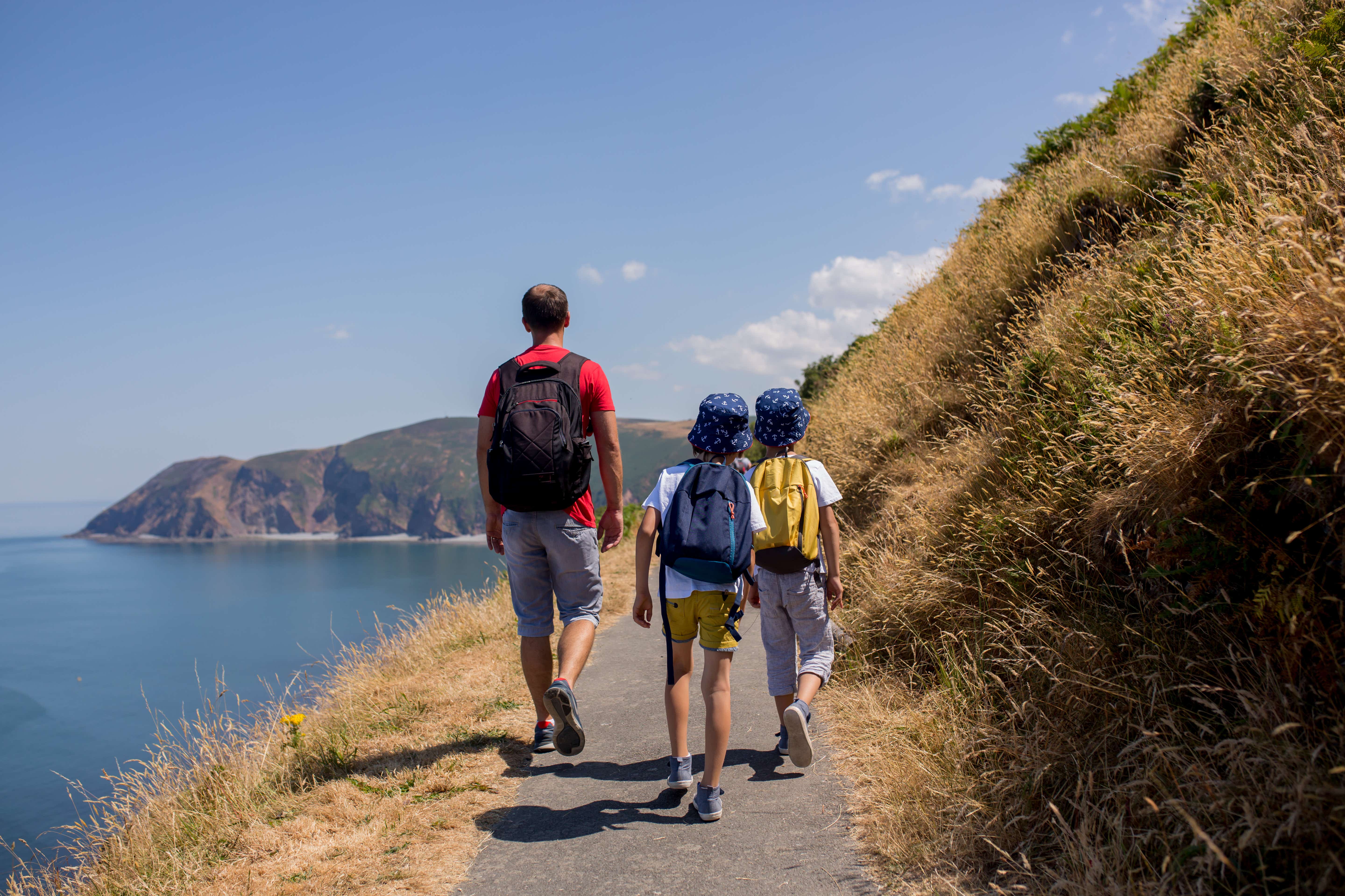 Father and sons walking along the coastline in the UK