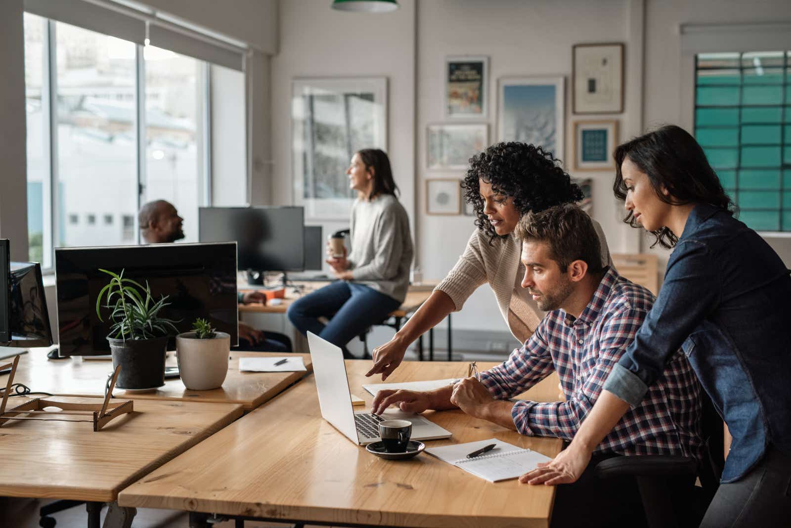 Colleagues gathered around a laptop in a modern office.