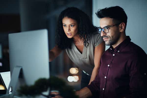 Co-workers looking at a monitor late at night