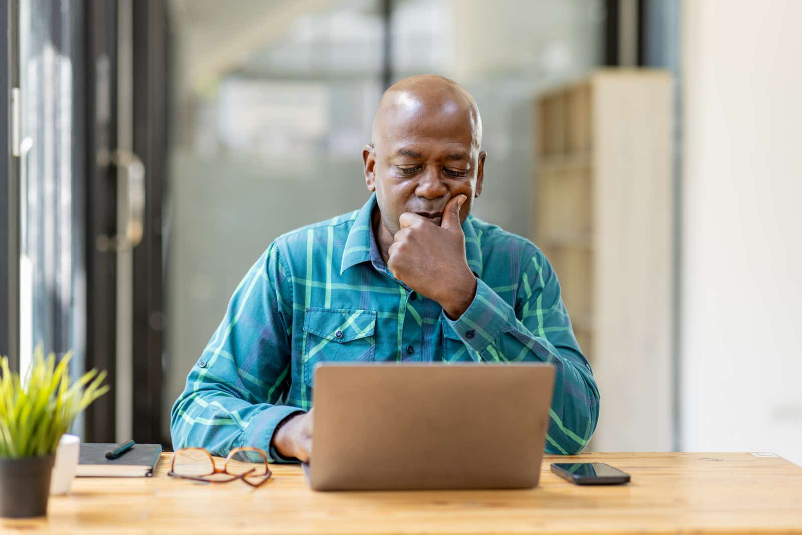 A businessman working on a laptop, considering what's on his screen.