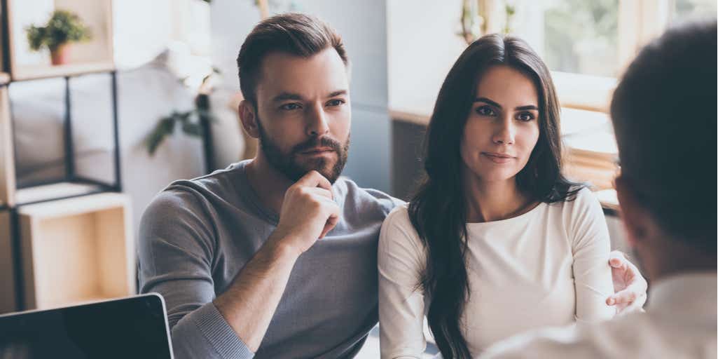 Photo of young couple listening to some man sitting in front of them at the desk