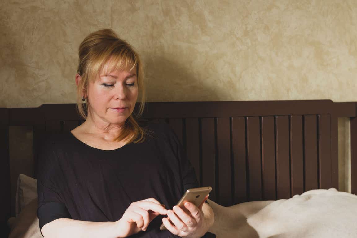 A seated woman looks something up on her phone.