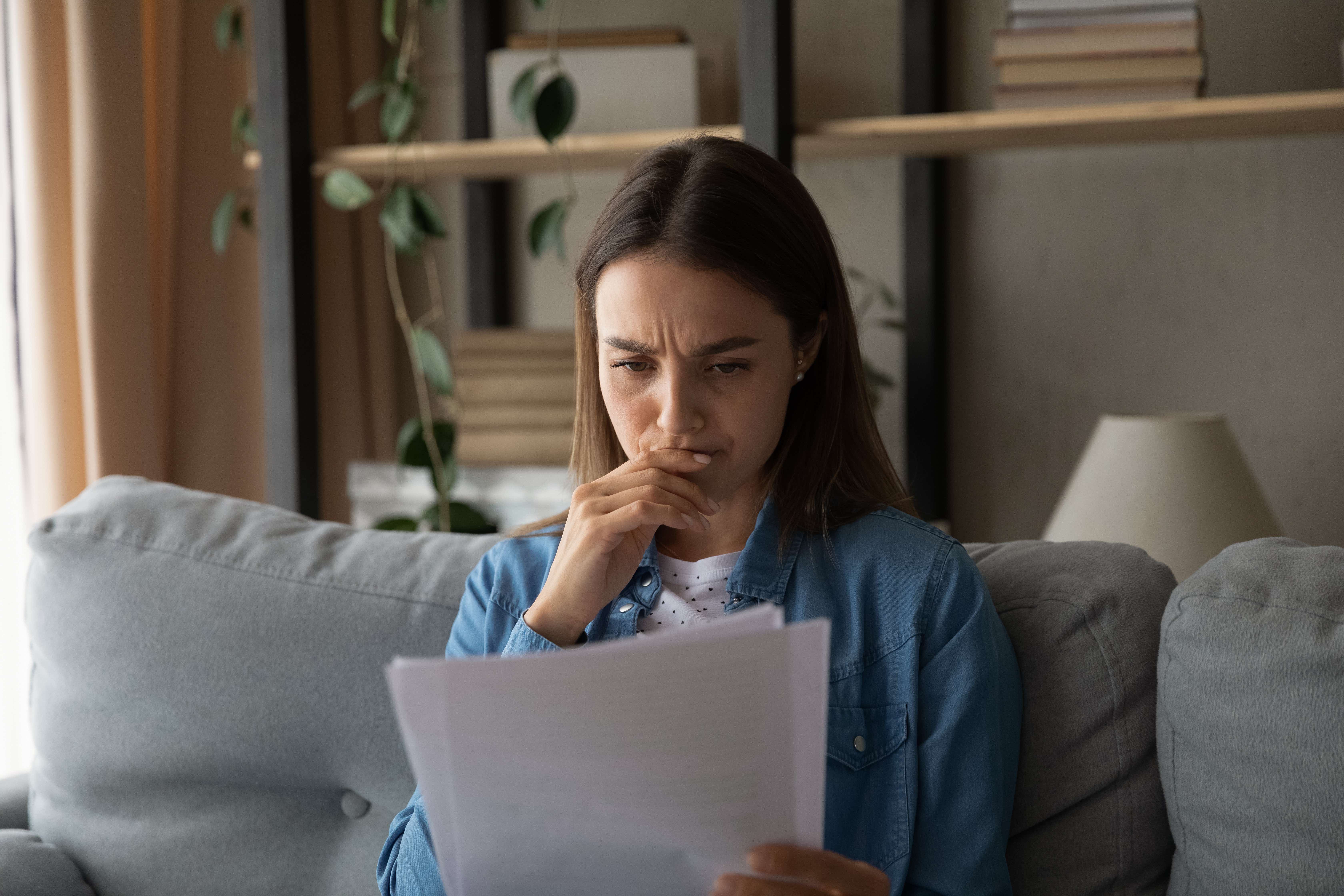 A worried-looking woman looks at paperwork.