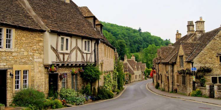 Empty road through a village, with small houses on either side of the road.