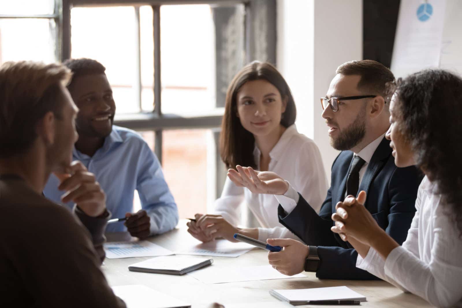 Businessman presenting his idea to a group of people gathered around a meeting room table.