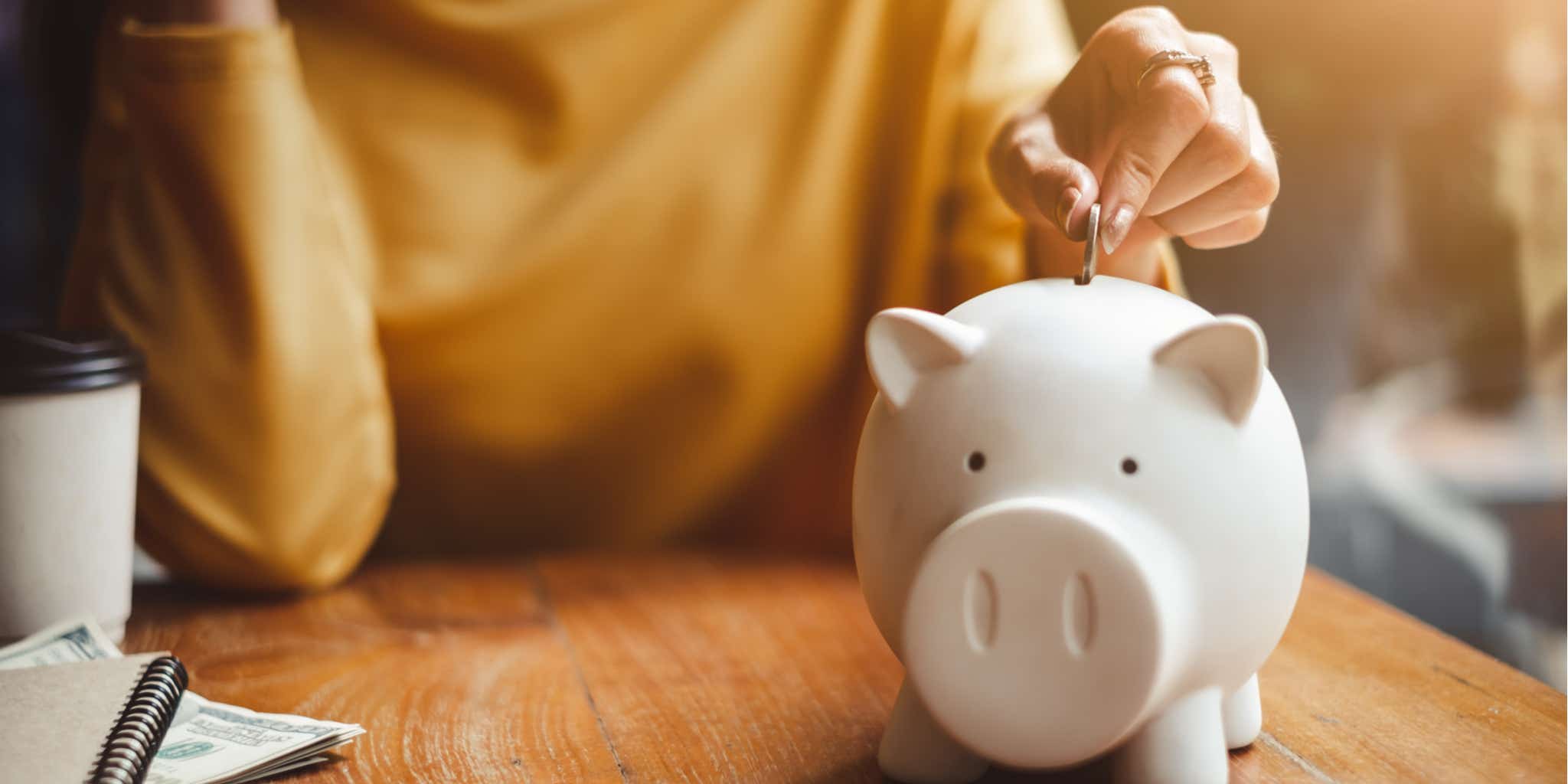 Lady putting money in piggy bank 