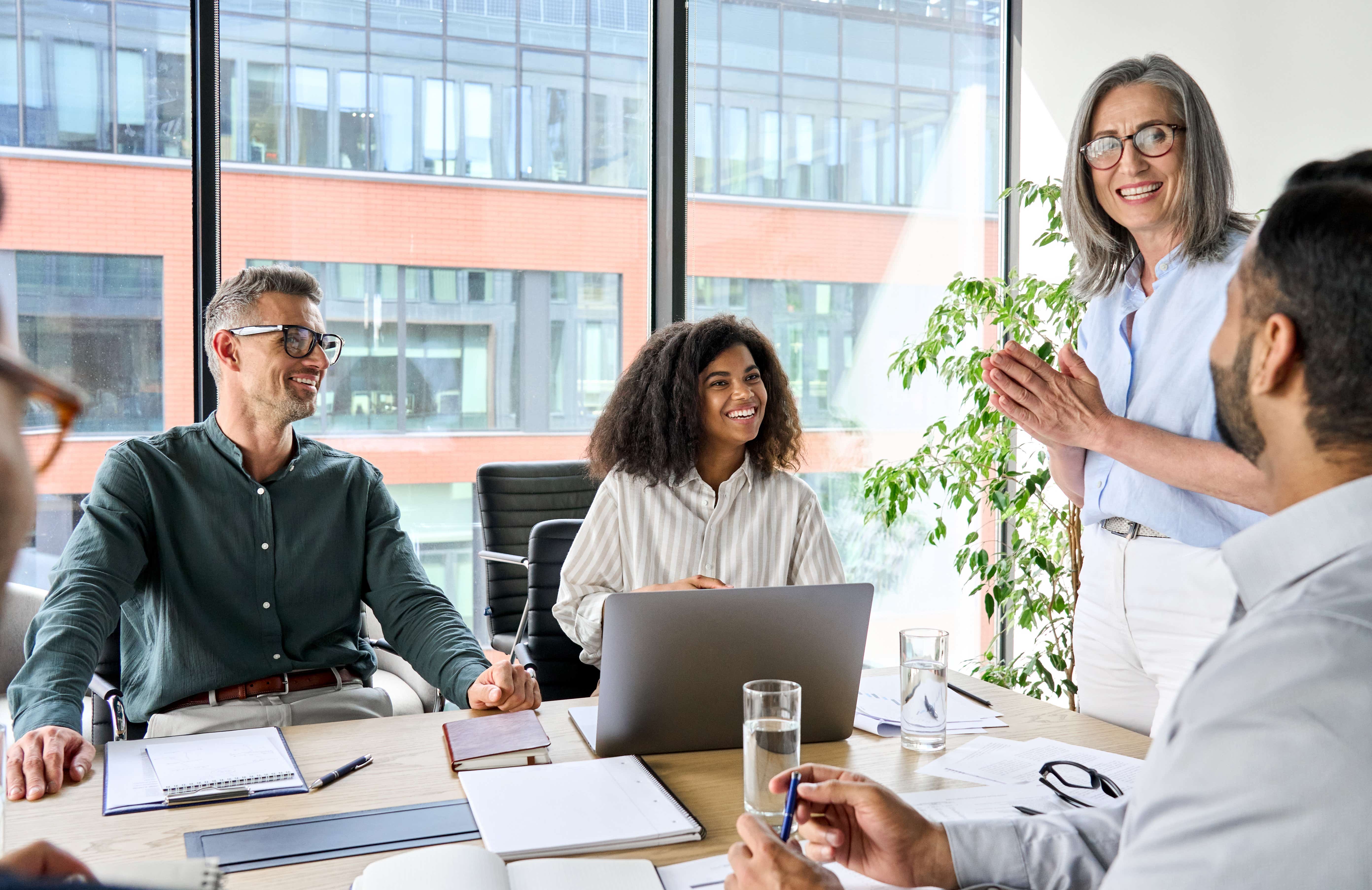 Female-led company, workers in office space gathered around a table talking