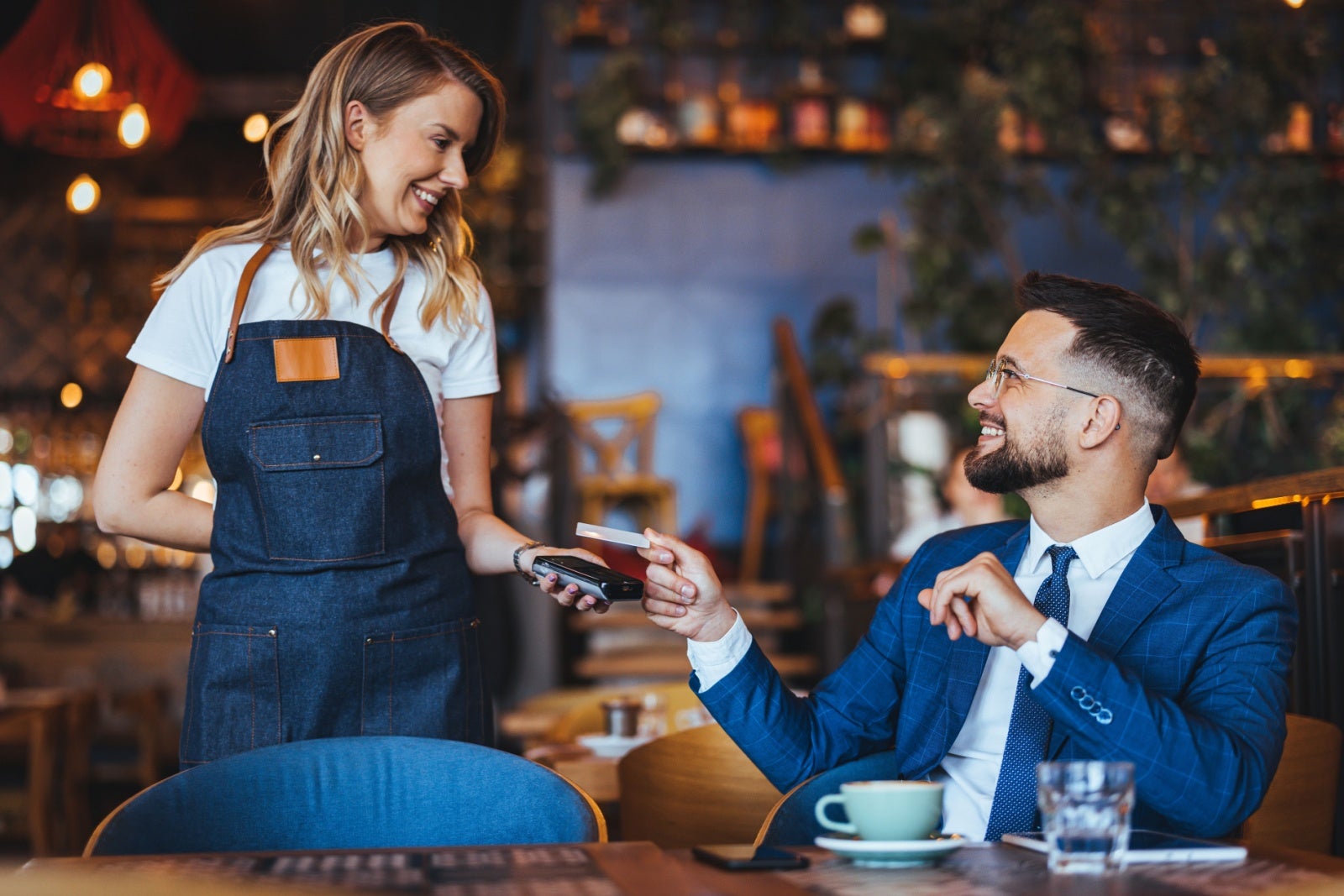 Man makes a card payment to the owner of a cafe.