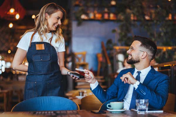 Man makes a card payment to the owner of a cafe.