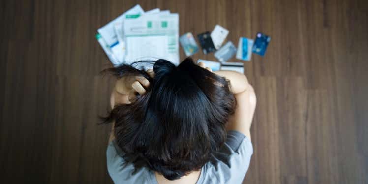 Woman looking at papers and credit cards on the floor, whilst gripping her name.