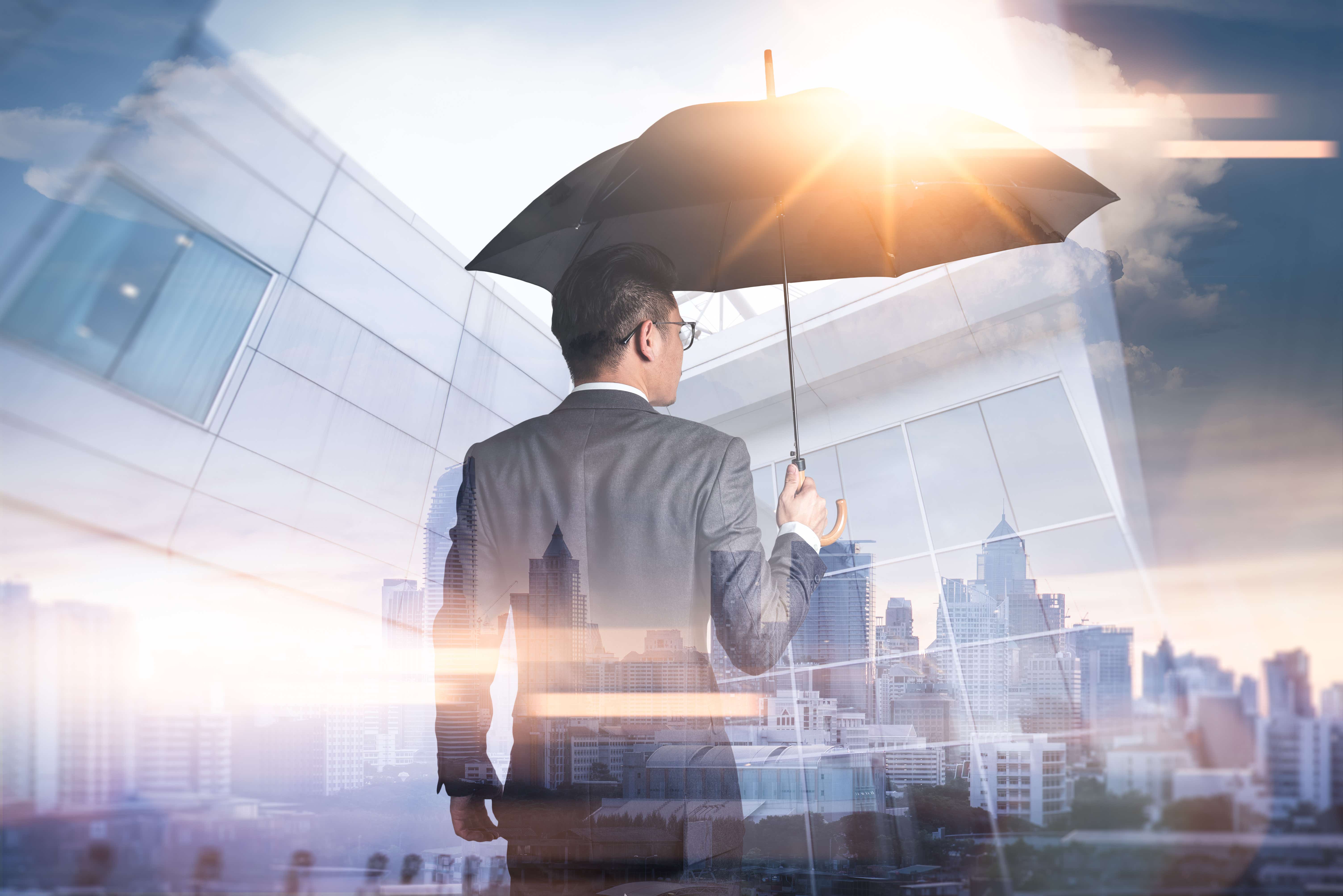 A man holds an umbrella below a sunny sky