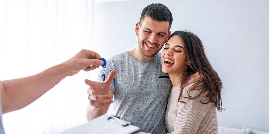 Young couple taking keys of their new house from broker.