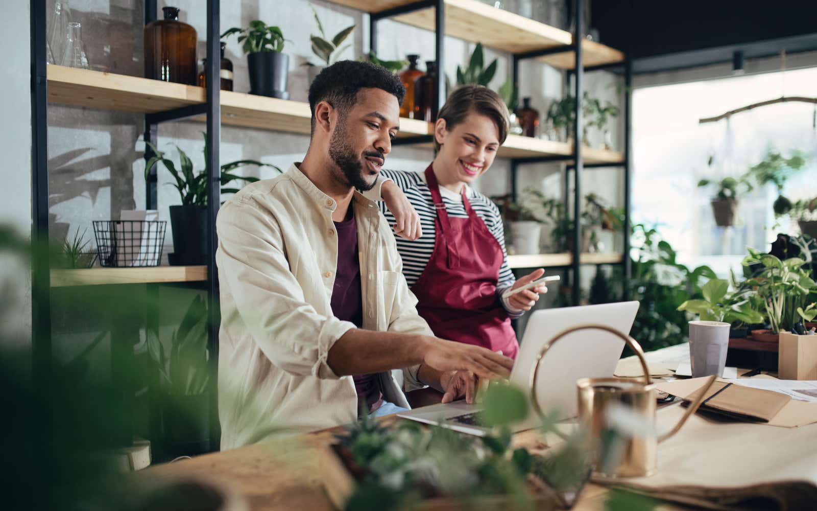 Shop assistants with laptop working in potted plant store