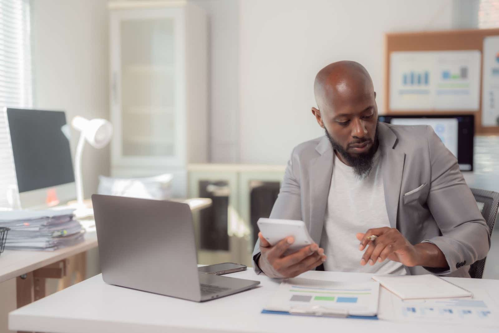 A businessman runs calculations while reviewing paperwork