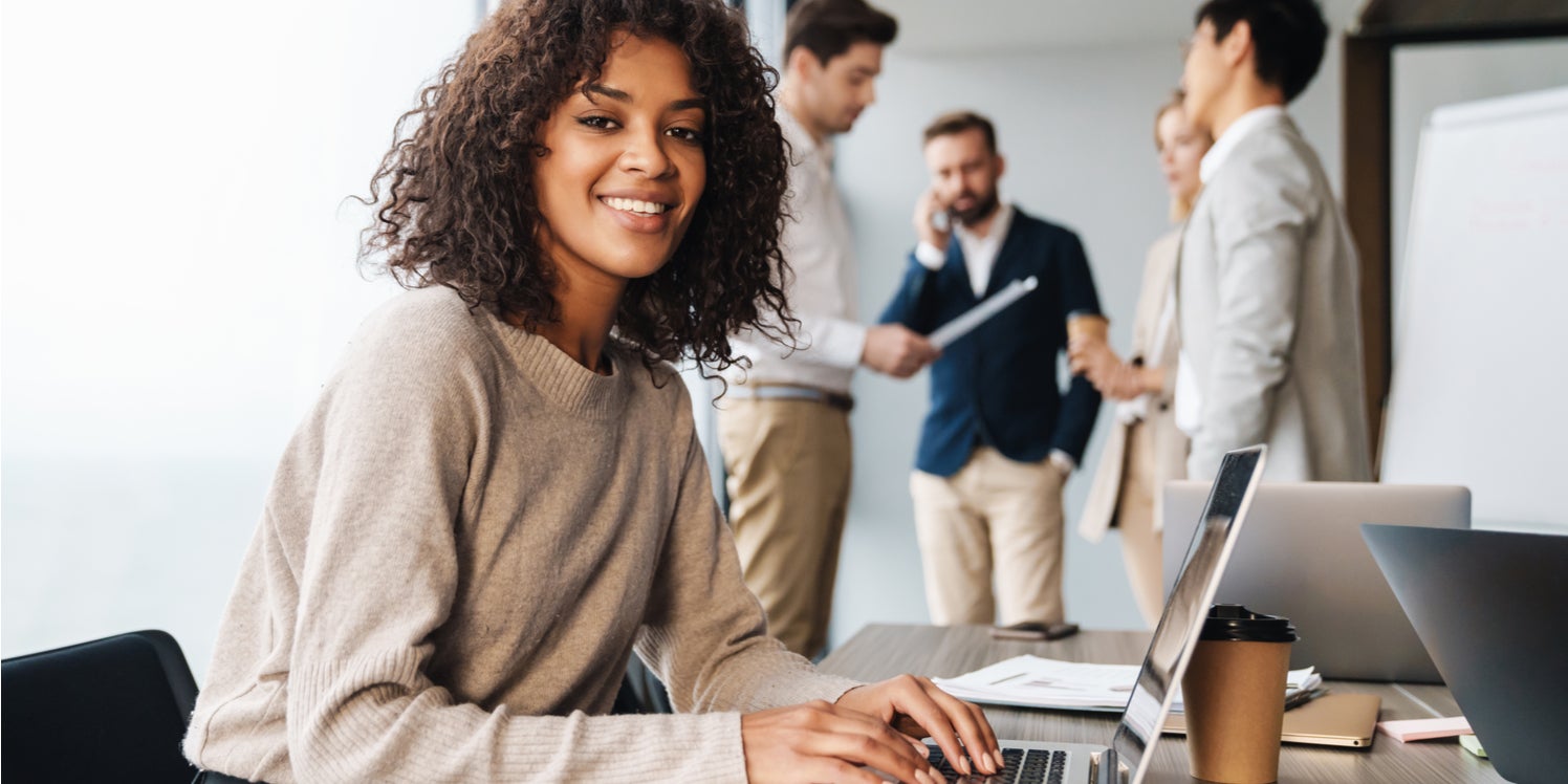 Confident woman smiling as her male colleagues panic about what to do