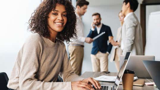 Confident woman smiling as her male colleagues panic about what to do