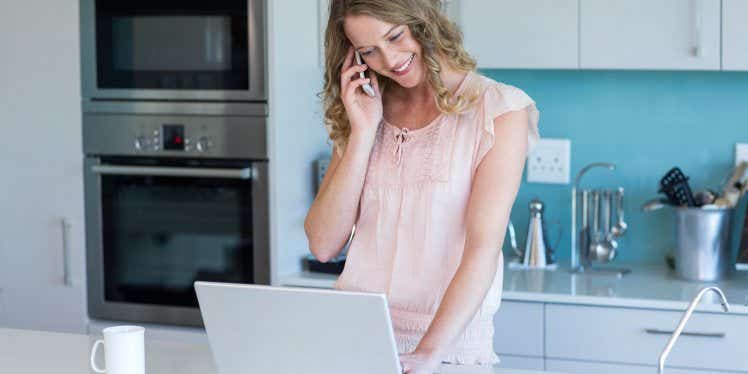 woman-on-phone-in-kitchen-with-laptop.CDN5e66117f