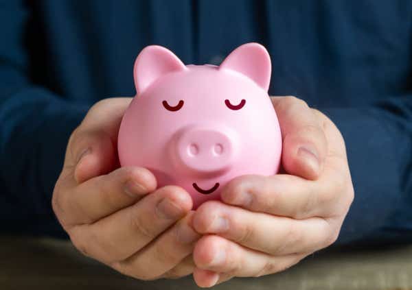 Close up of a relaxed piggy bank cradled in someone's hands.