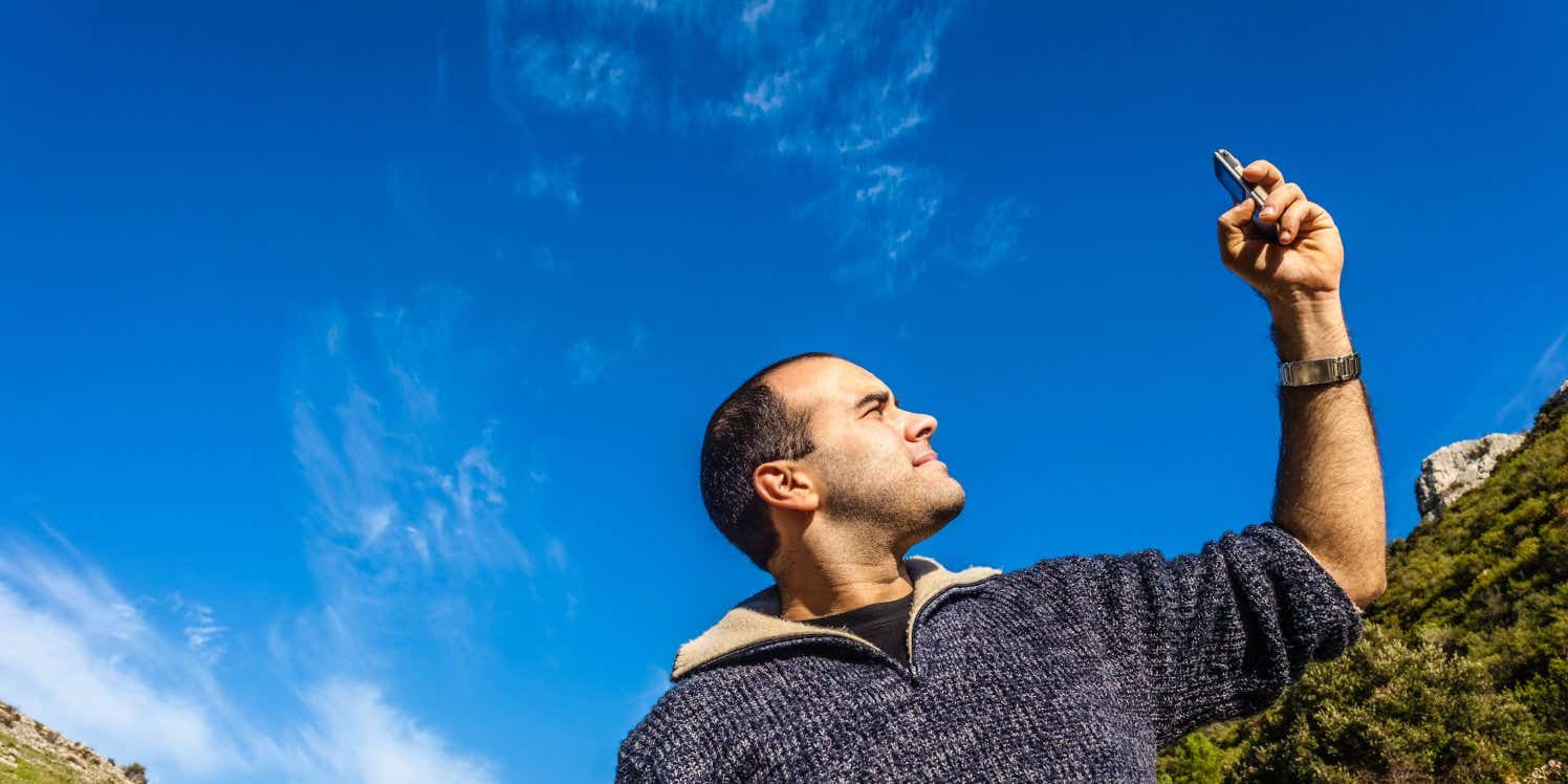 Man holding phone up to search for signal