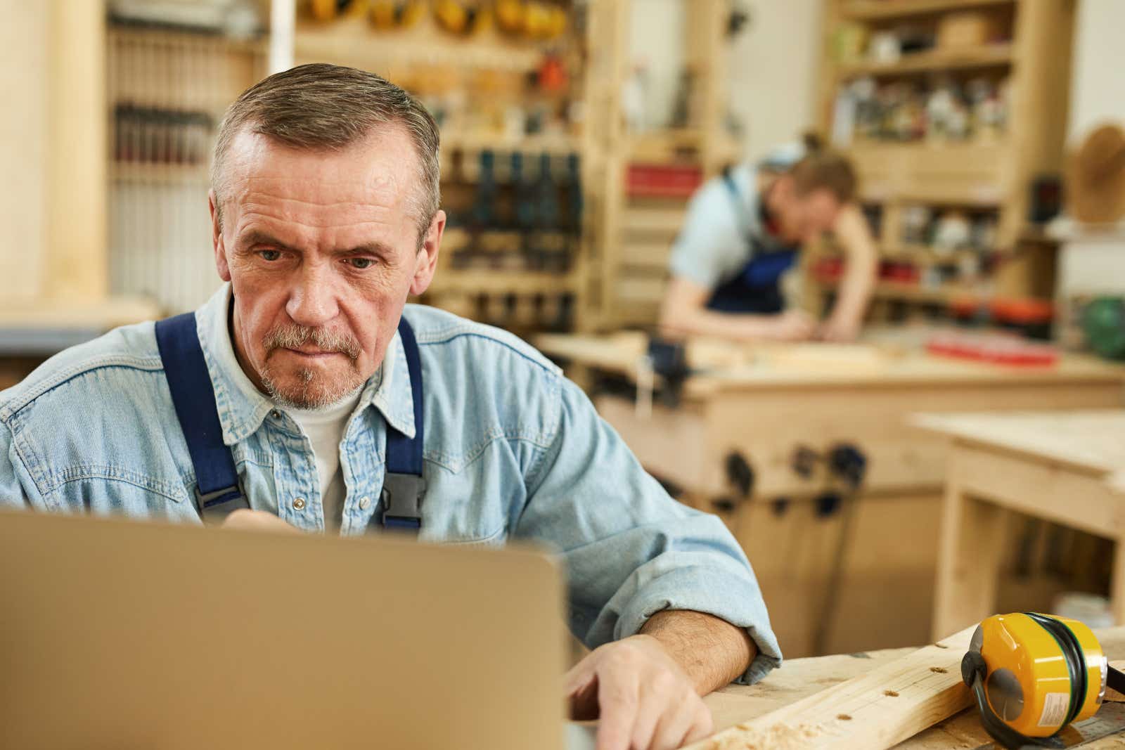 Carpenter using a laptop while working in a joinery