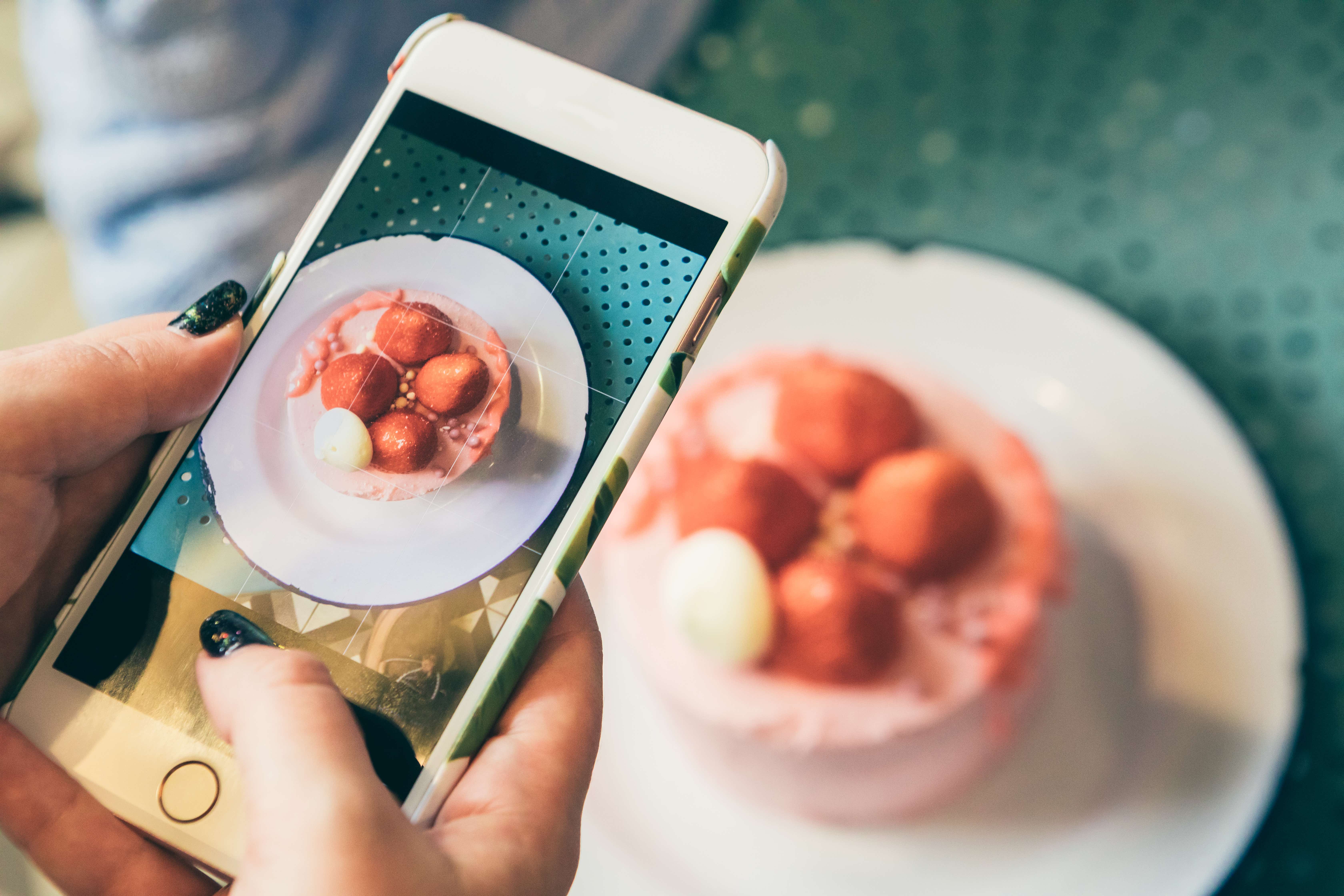 Photo of a woman taking a photo of a cake.