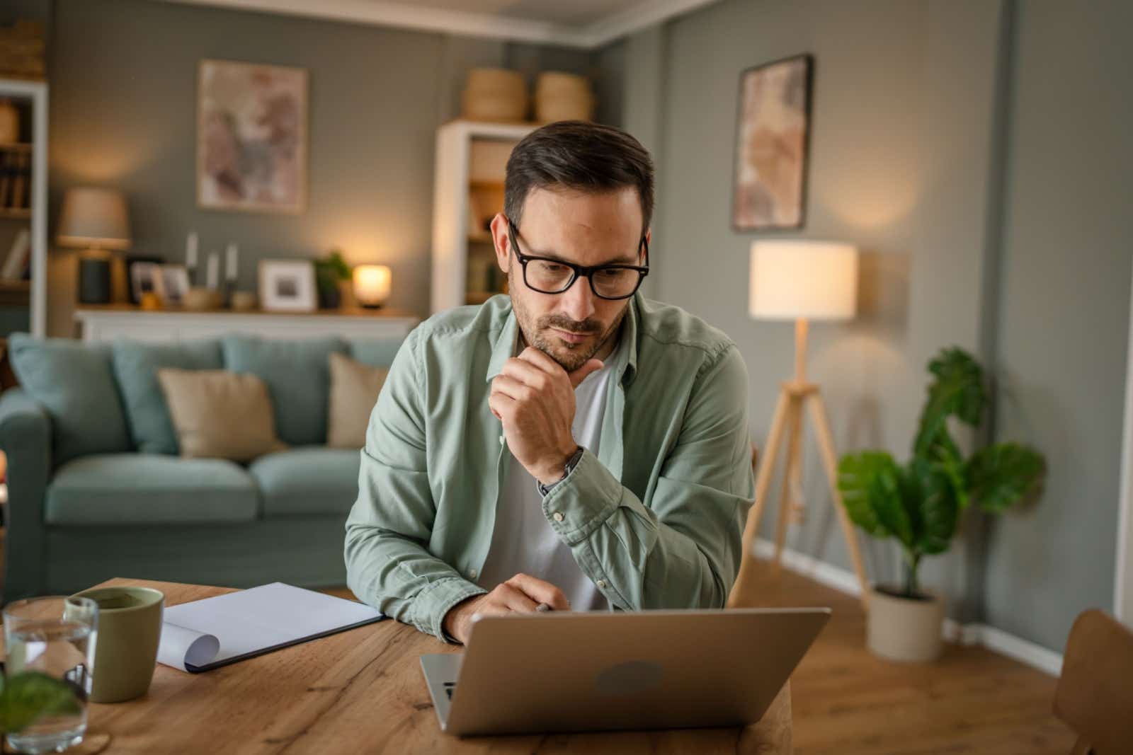 Business man working from home contemplates his laptop.