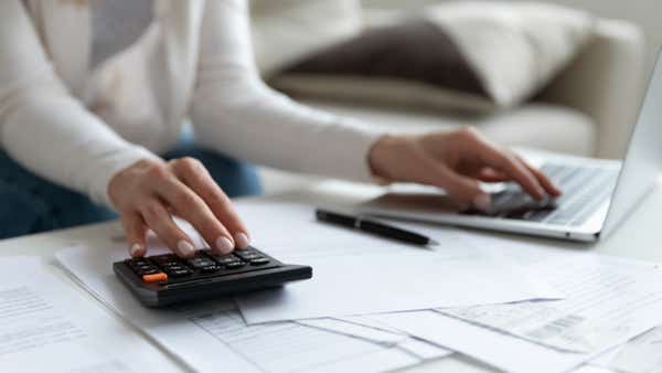 A photo of a person using a calculator and a laptop.
