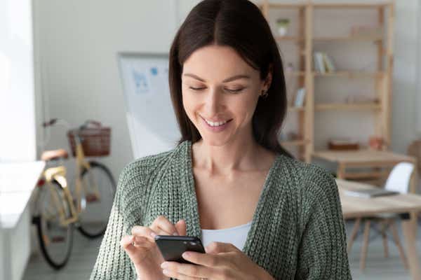 Casual business woman using her smartphone in a modern, cool office space