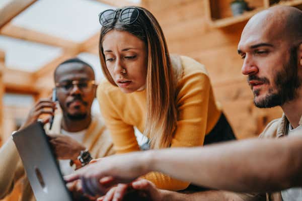 Business people gathered around a laptop.