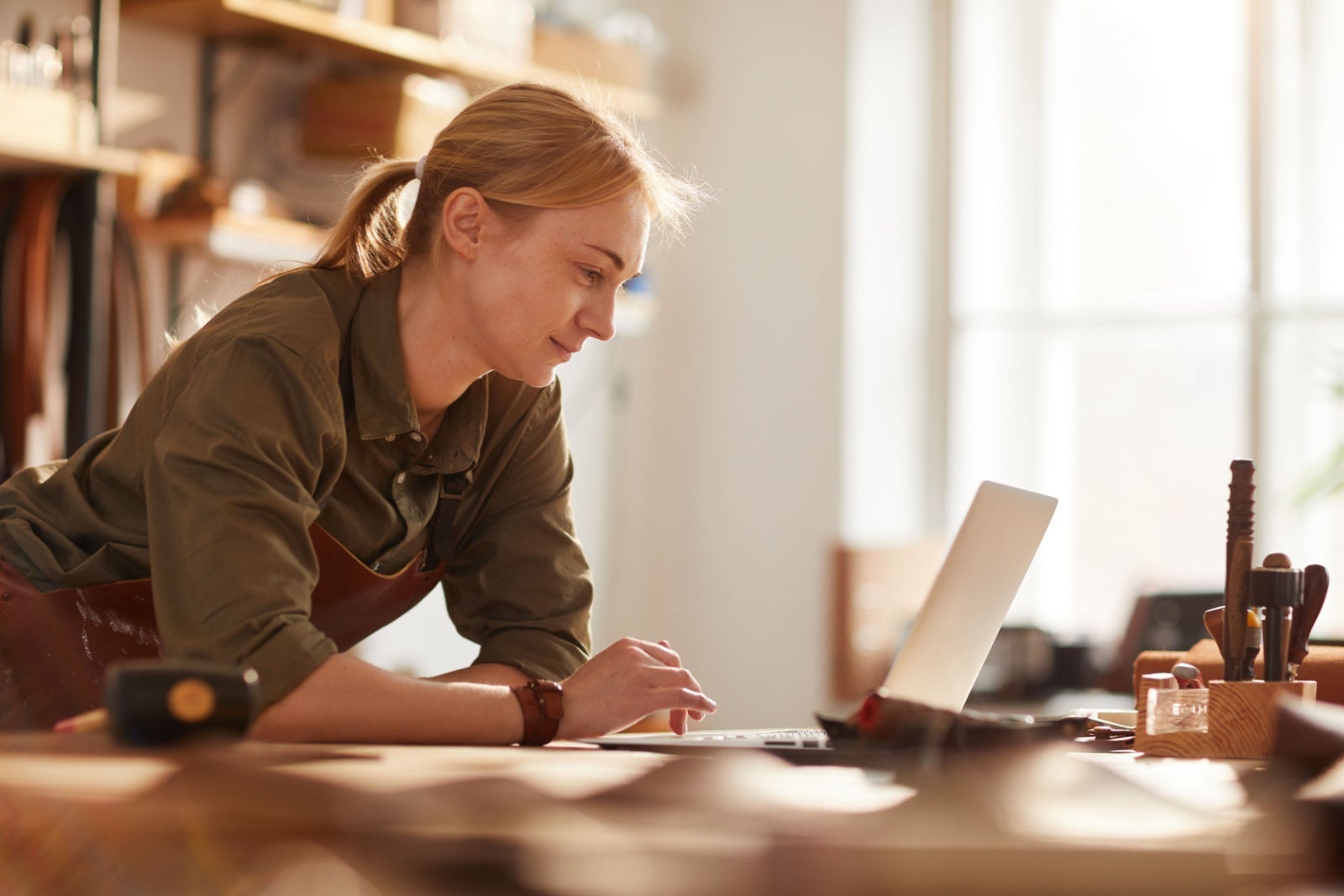 Craftswoman in her workshop using a laptop