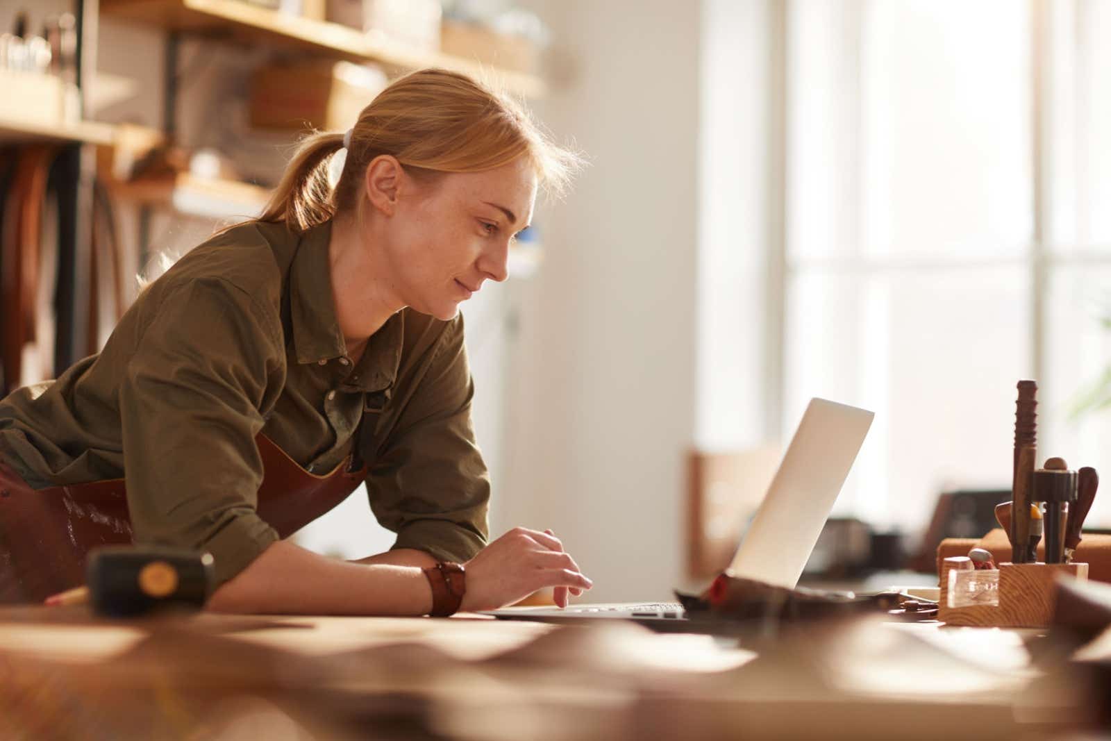 Craftswoman in her workshop using a laptop