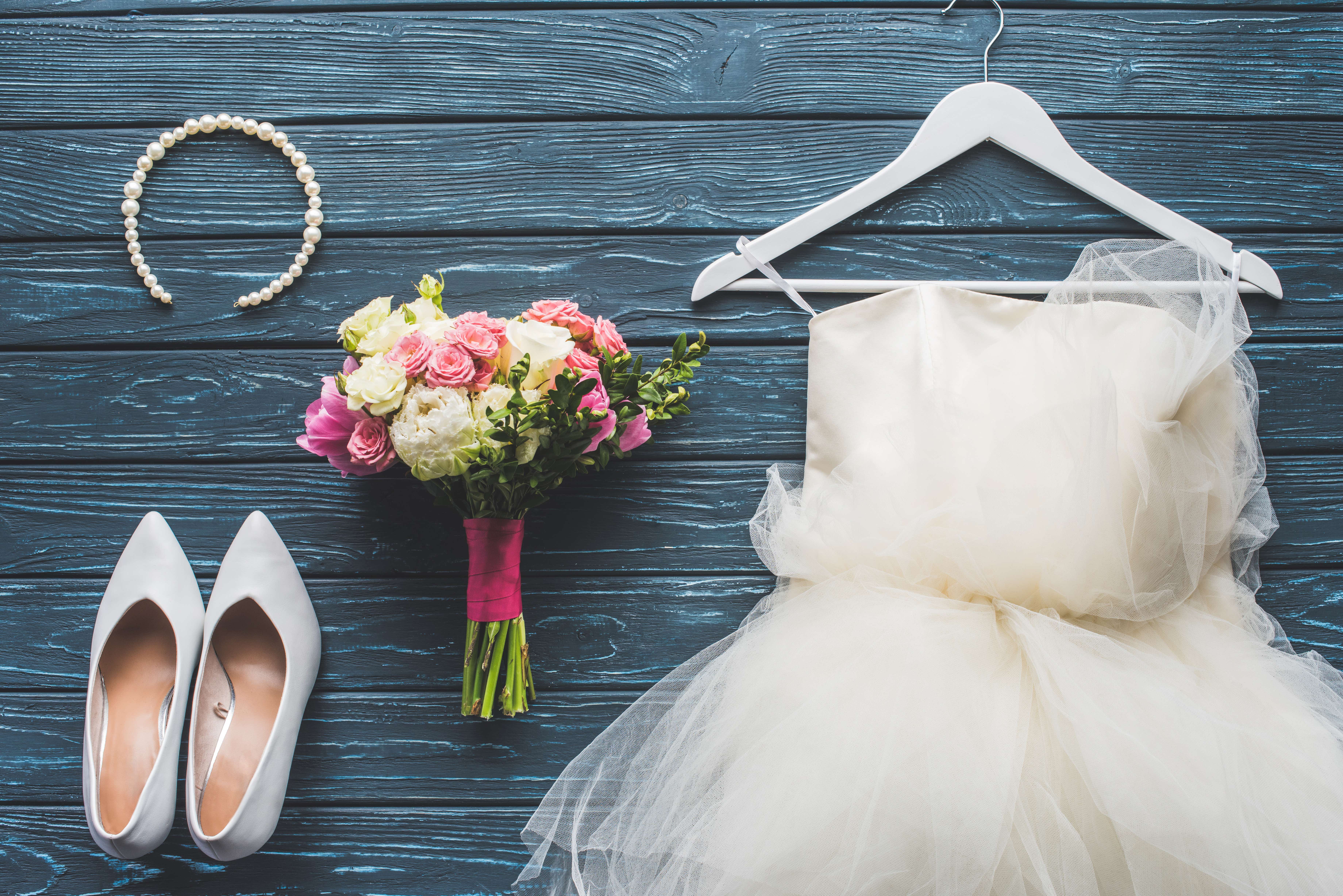 top view of wedding bouquet and dress on wooden dark blue tabletop