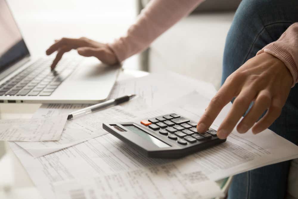 Close up of a woman's hands with a laptop and calculator next to her. 