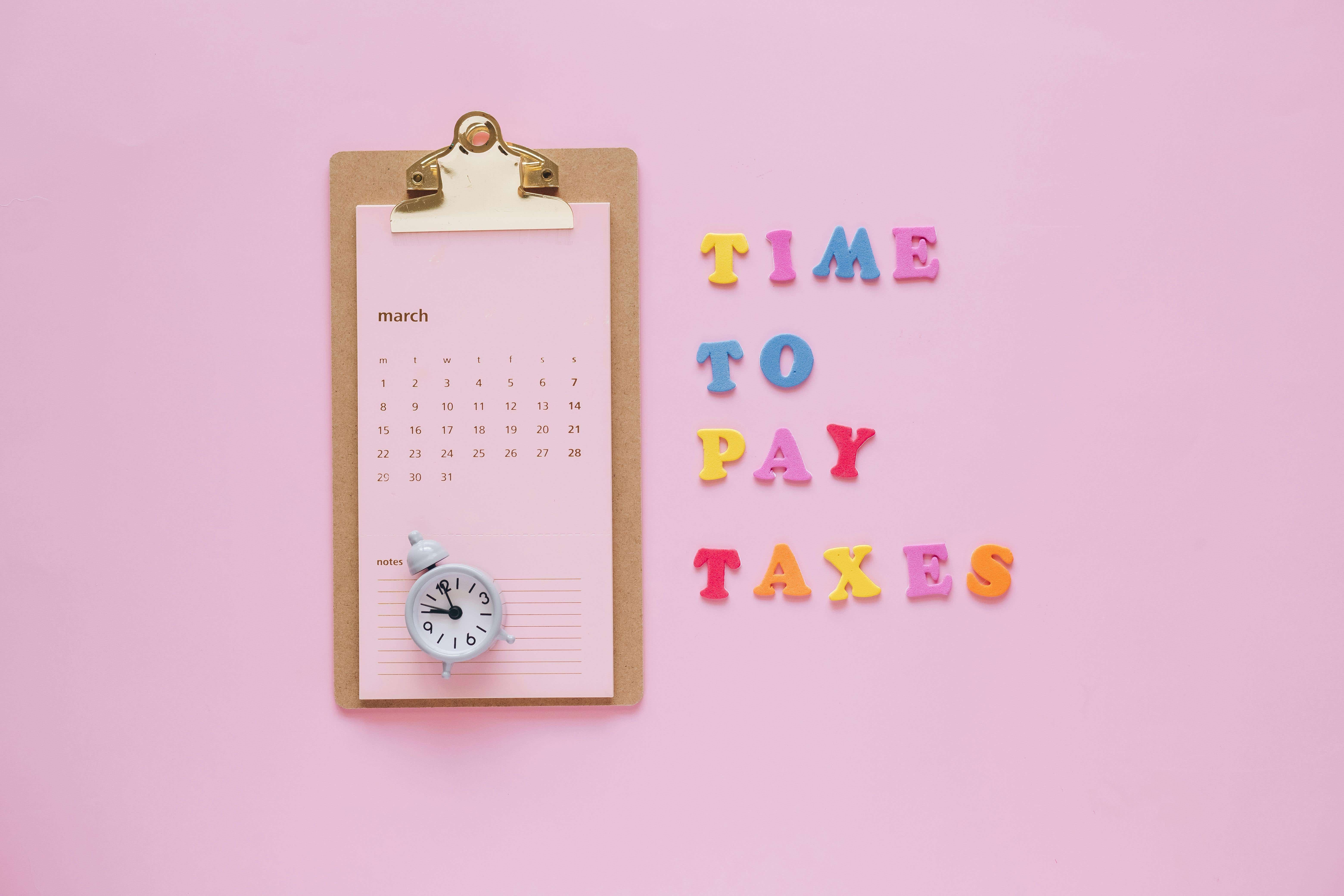 Note pad with a calendar and block letters "Time to pay" next to it