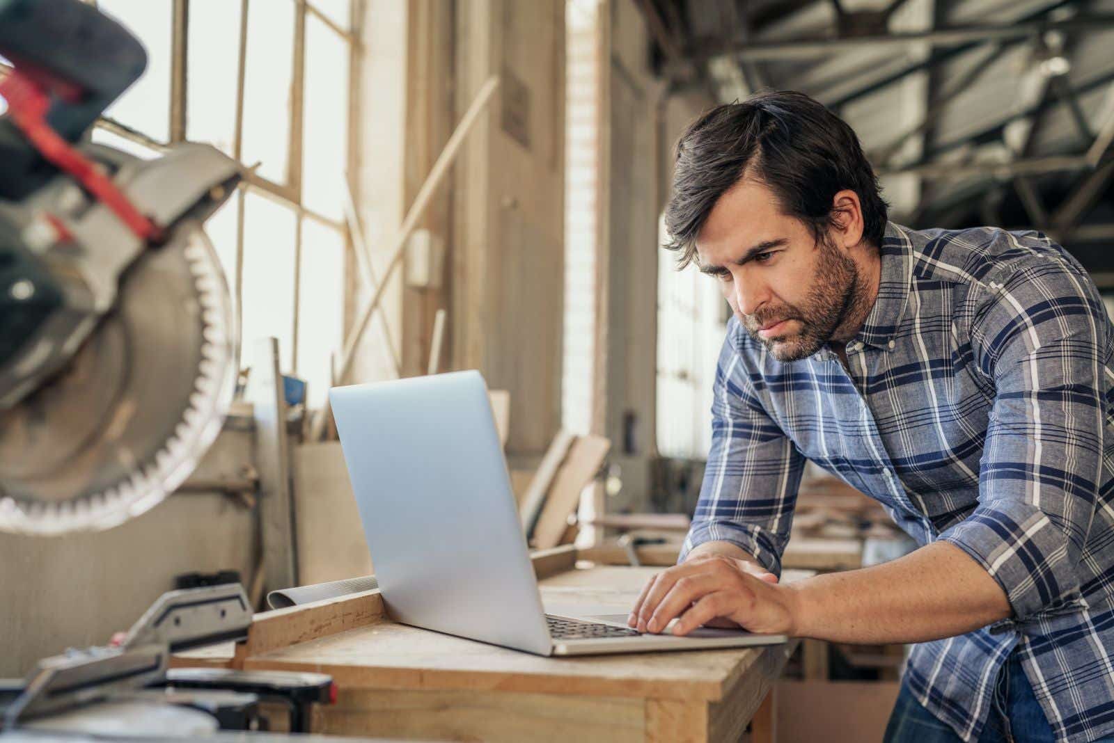 Man in a workshop stares at his laptop.