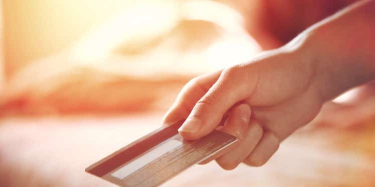A person holding a cashback credit card in their hand and using this for payment 